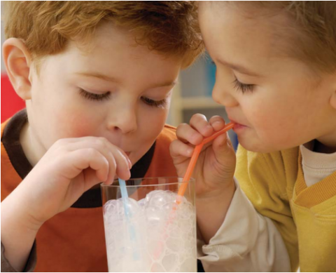 two kids sharing a glass of milk