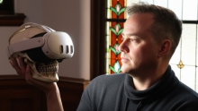 Peter Kuling holding a skull that is a wearing a VR headset. 