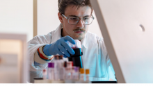 A man in a white lab coat working in a lab.