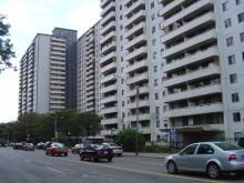 Cars stopped on a street in front of an apartment building in St. James Town.