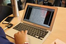 Someone using a MacBook Air computer to look at a handwritten document.