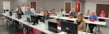 Men and women sitting at desks with computers in a classroom