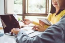 A woman and man sitting at a laptop.