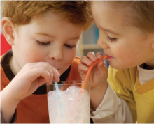 two kids sharing a glass of milk