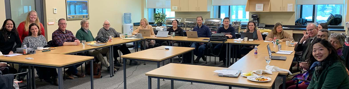 A large group of adults sitting around a table with their laptops