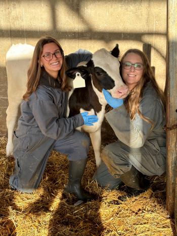 Two women posing with a black cow