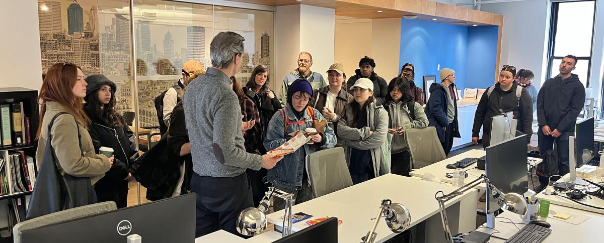 Students standing in ERA Architects office listening to the Principal
