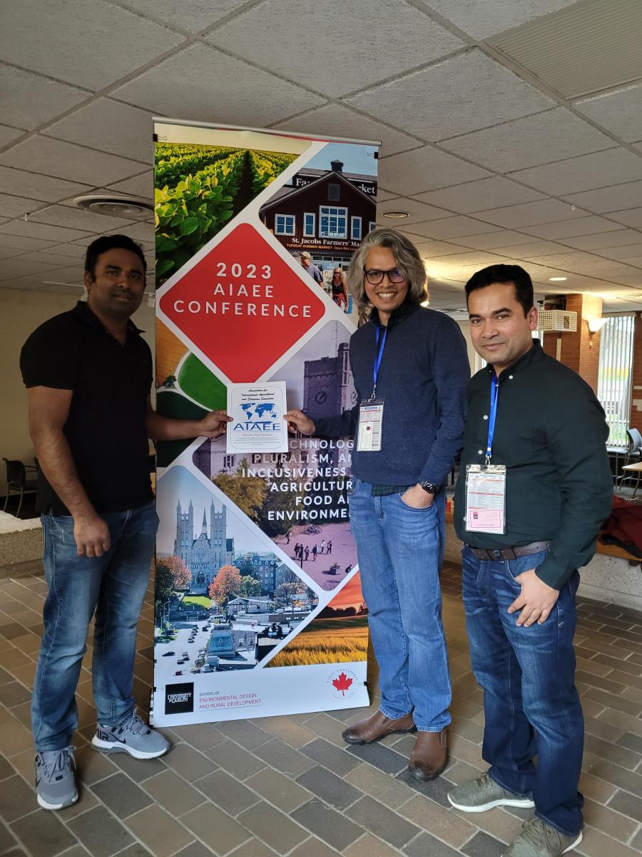 Three people standing in front of conference banner