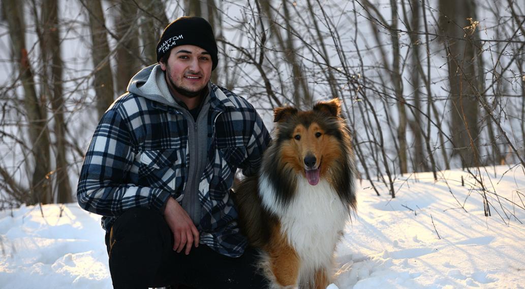 man on one knee holding dog in a winter forest