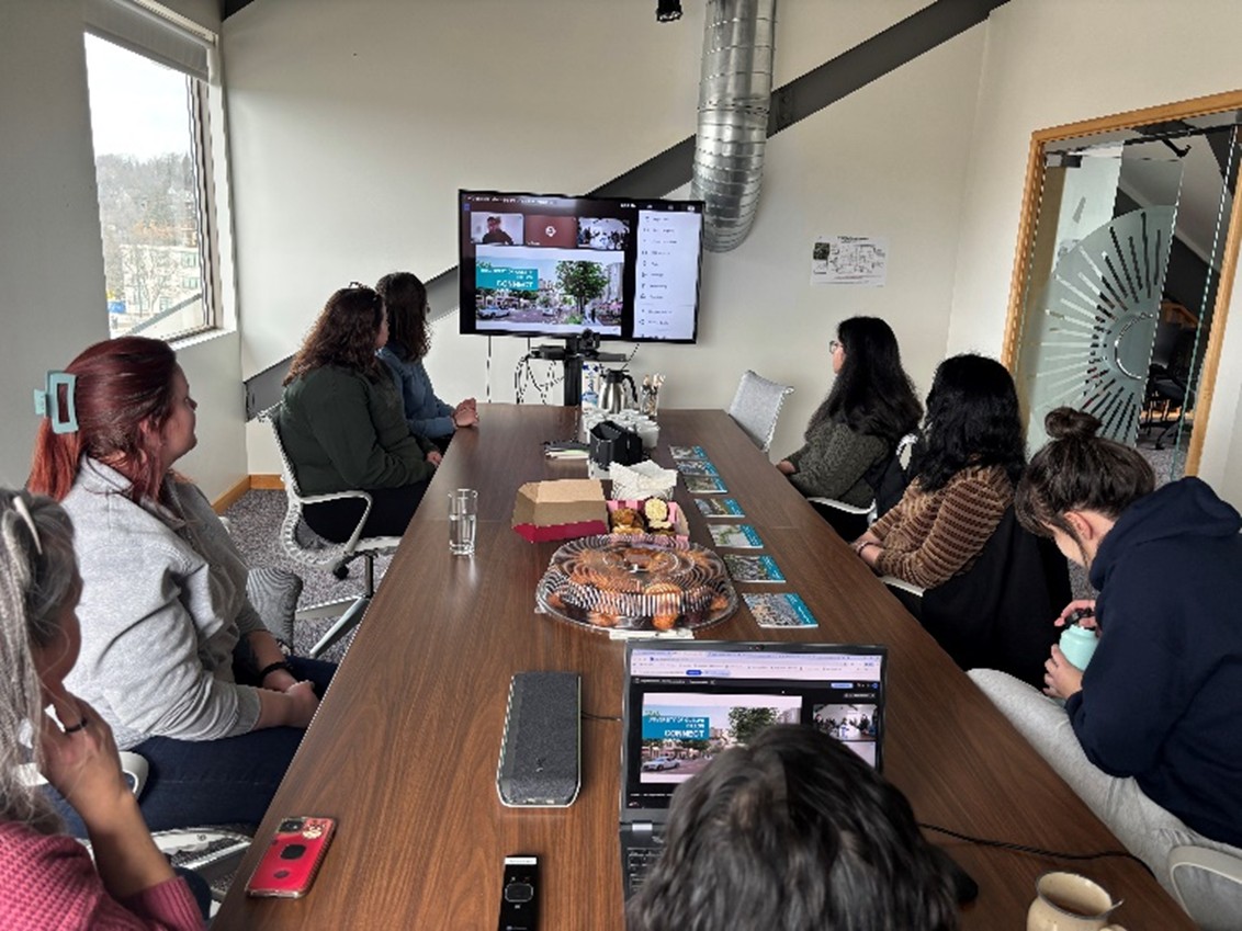 Students sitting around a table looking at a TV screen.