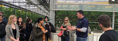 Students inside the greenhouse listening to owner