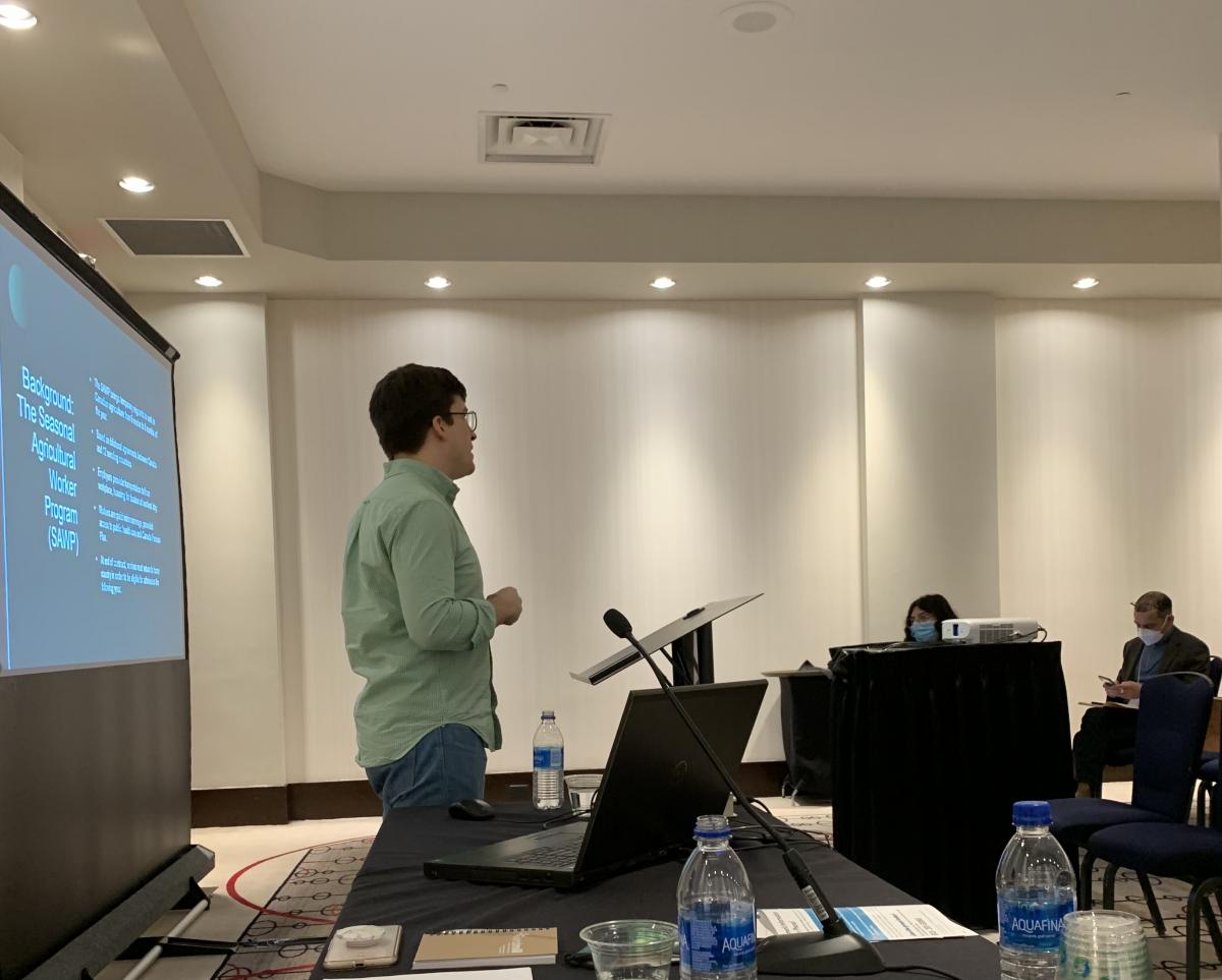 student in front of screen presenting at a conference