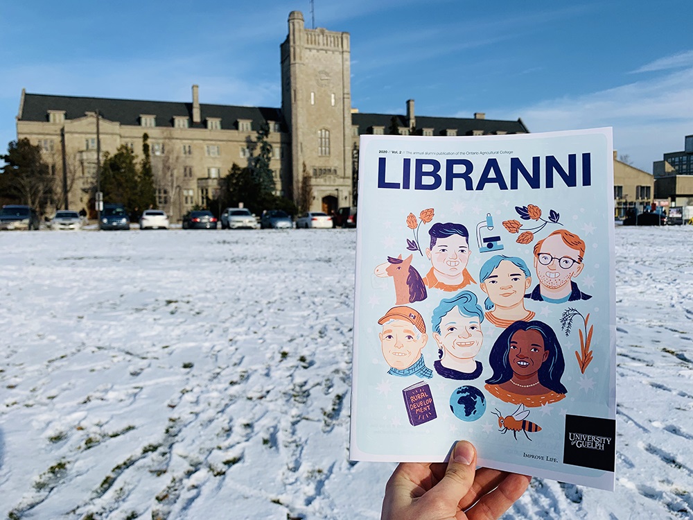 Person holding copy of magazine in front of Johnston Hall