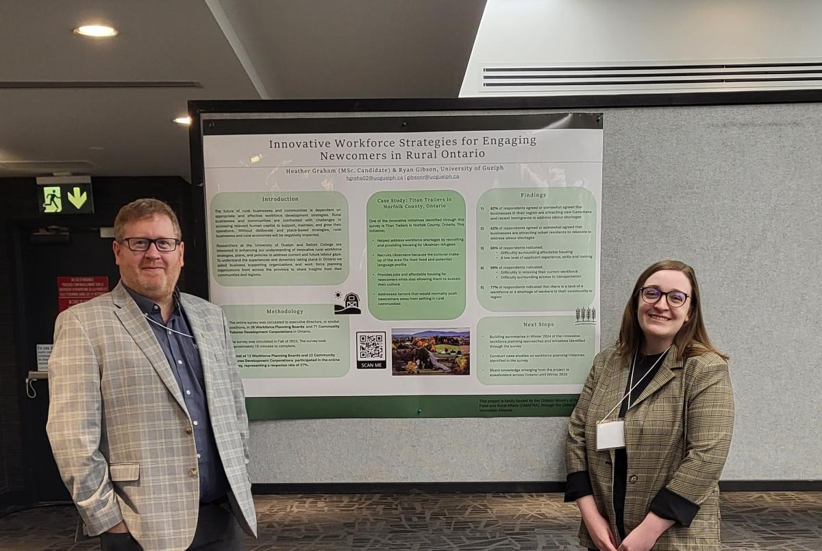 Ryan Gibson and Heather Graham standing by their poster presentation