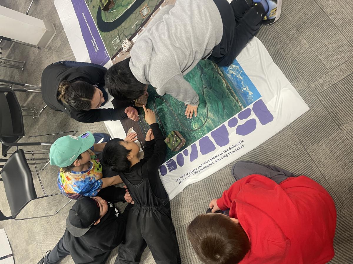Elementary students on the floor looking at permafrost map