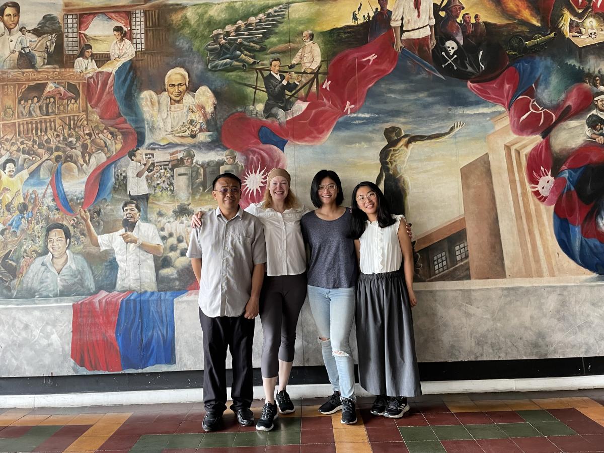 Four students standing in front of wall mural