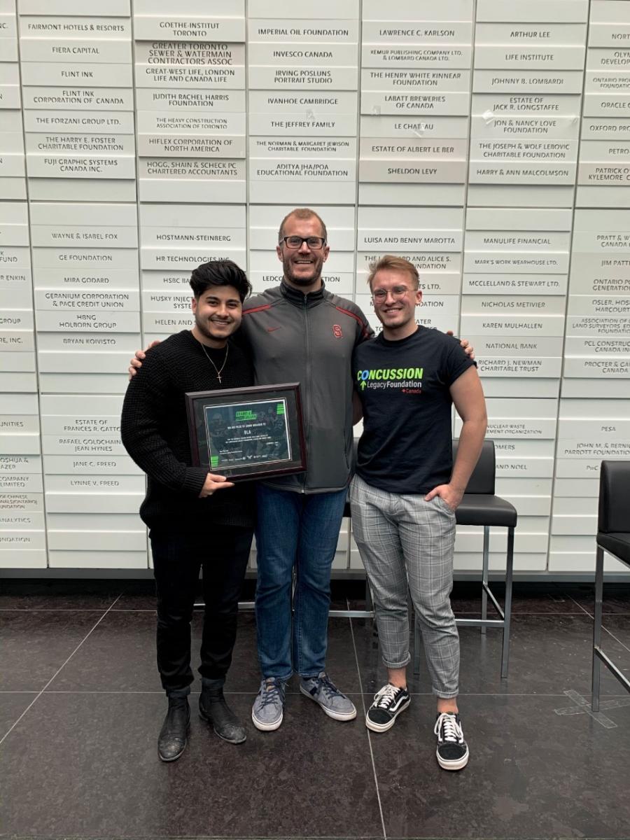 Students posing with award frame