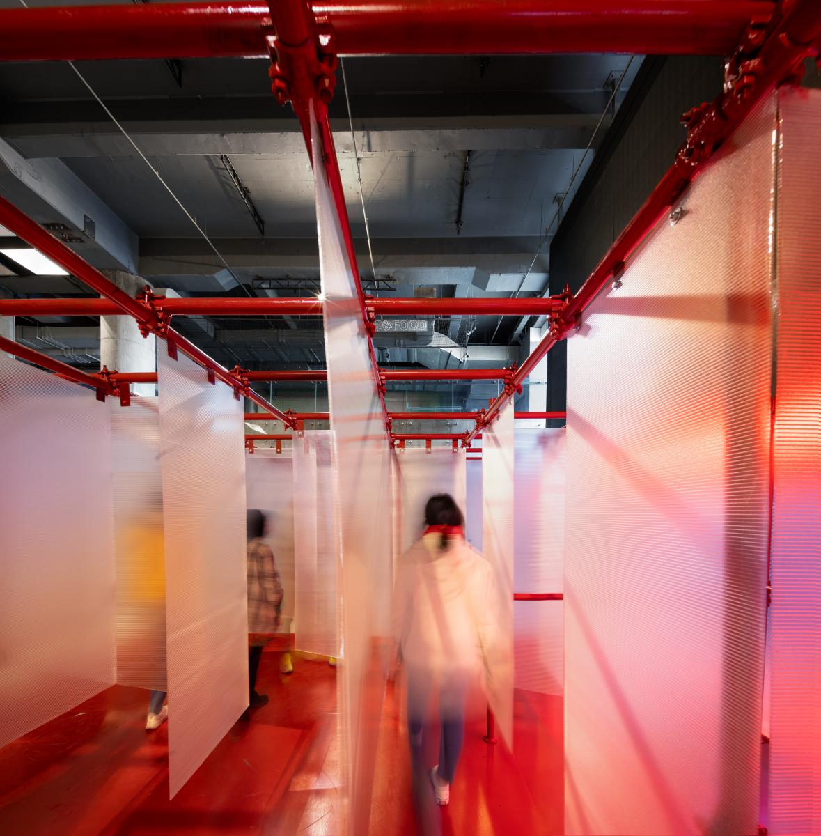 People walking through constructed red labyrinth