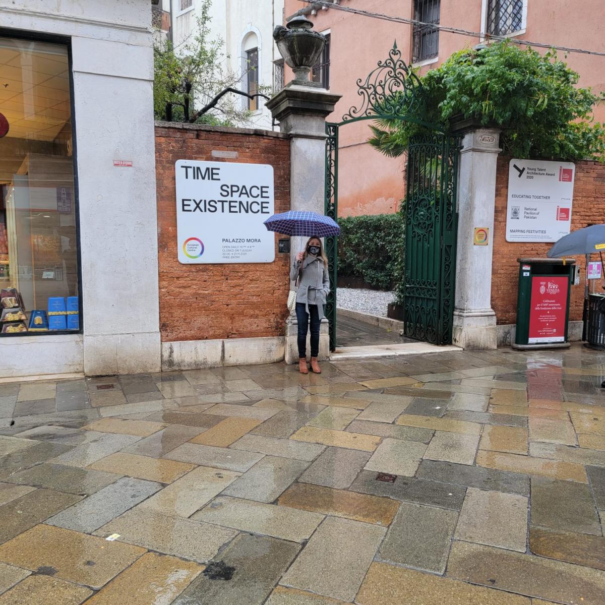 Nadia Amoroso standing outside of the Plazzo Mora building holding an umbrella