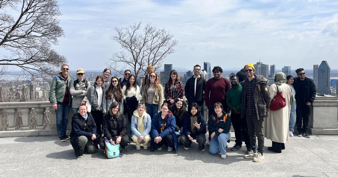 Field trip participants standing and kneeling on the Kondiaronk Belvedere overlooking Montréal
