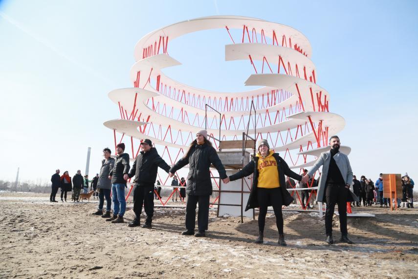People holding hands in front of "OneCanada" design installation at Woodbine Beach 