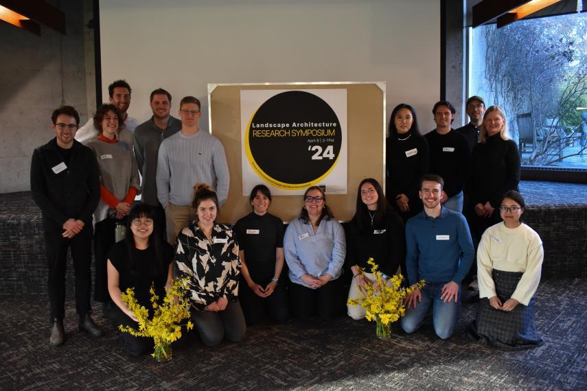 MLA students standing and kneeling in front of research symposium poster