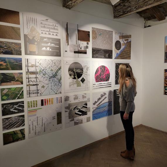 Prof. Nadia Amoroso standing in front of digital drawings displayed on white wall