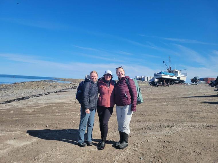Three researchers standing along the shore of Hudson Bay