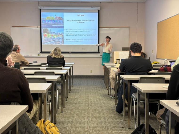 Dr. Geneviève Metson speaking in front of a seated crown