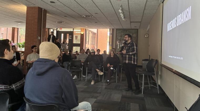 Grant Fahlgren in front of a projector screen talking to seated students.
