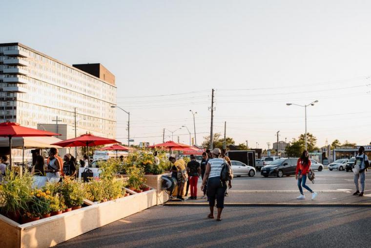 People walking past the WexPOPS site with flowers and umbrellas