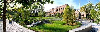 Panoramic photo of Shoemaker Green featuring trees, water and building