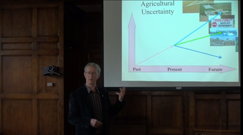 Wayne Caldwell stands infront of large presentation screen which reads "Agricultural Uncertainty"