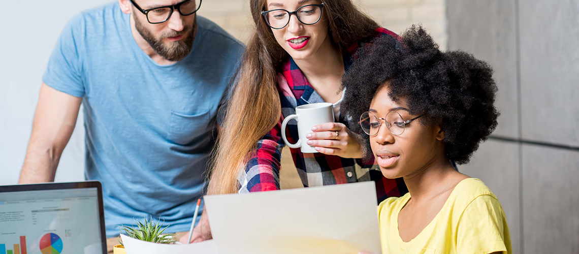 Three students at a desk discussing a project