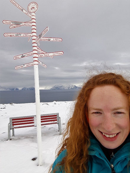 Hilary Sadowsky in front of sign post at Pond Inlet