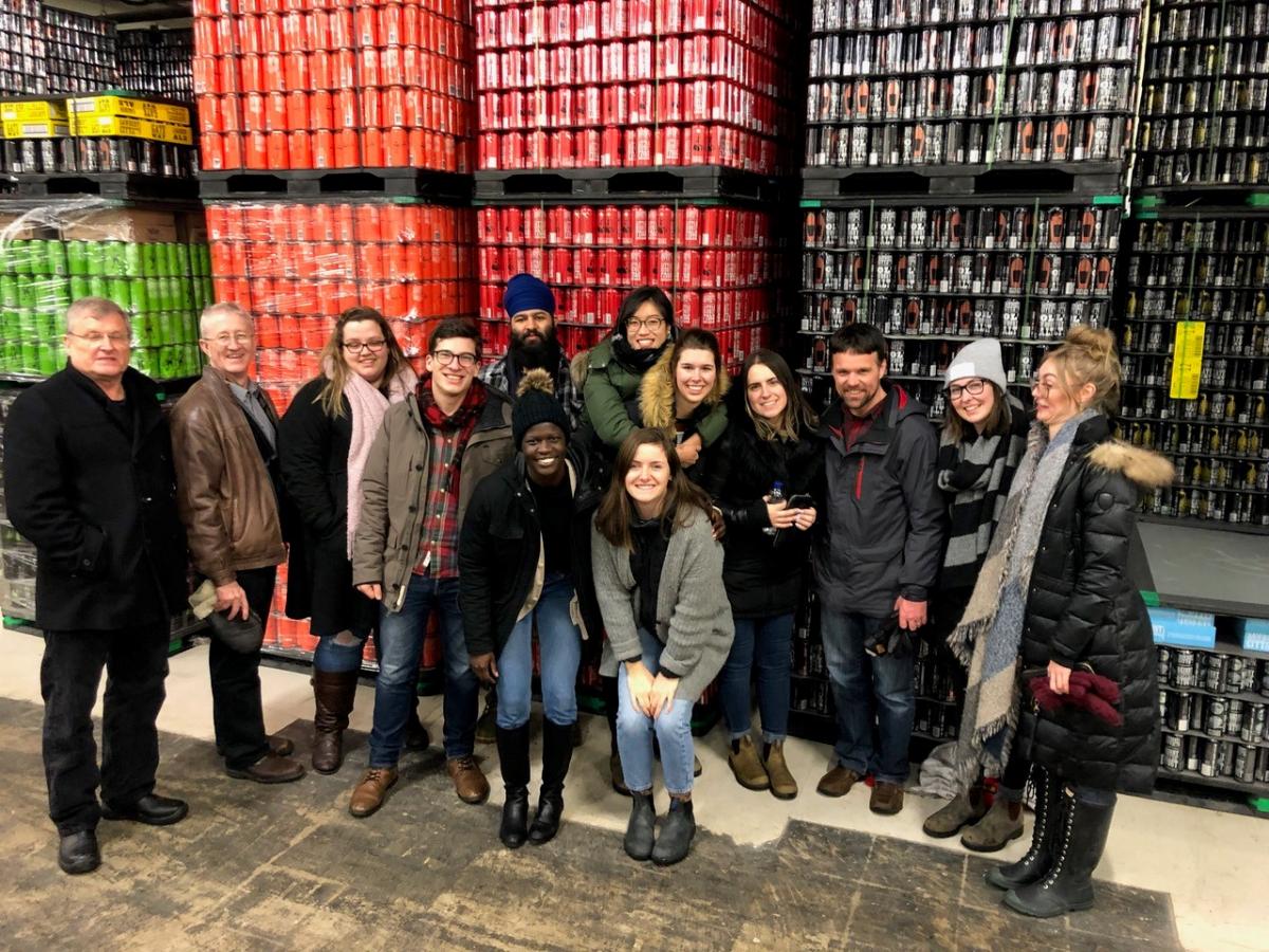 students in front of skids of beer cans