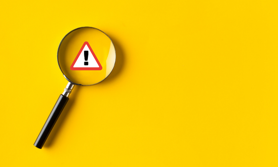 Magnifying glass finding hazard symbol